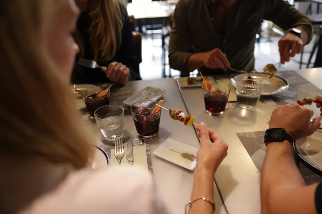 Personas disfrutando de vermut y tapas con gildas en una mesa en La Rosa Catalina