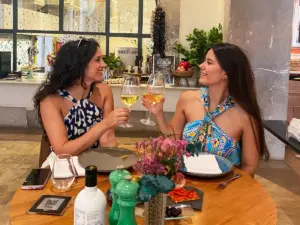 Two women toasting with glasses of white wine during a local dining experience at a restaurant in Palma de Mallorca